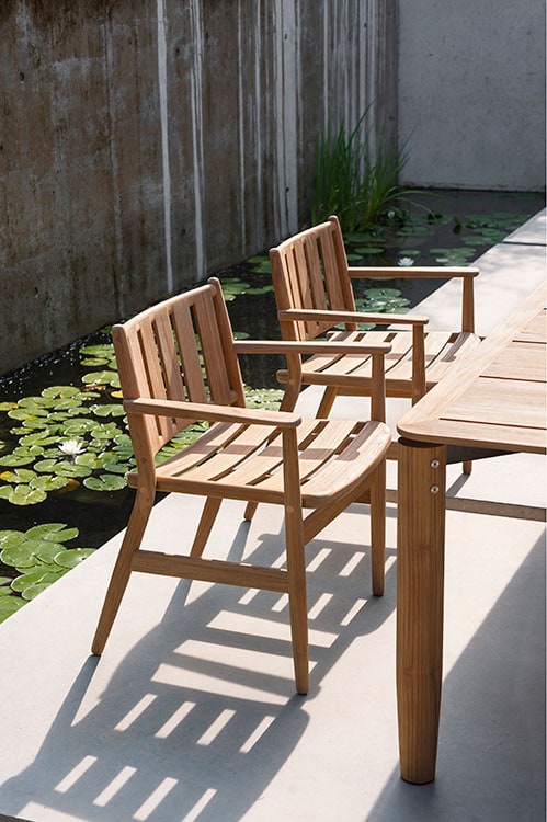 Pair of Levante One Armchair in front of a wooden table on a patio