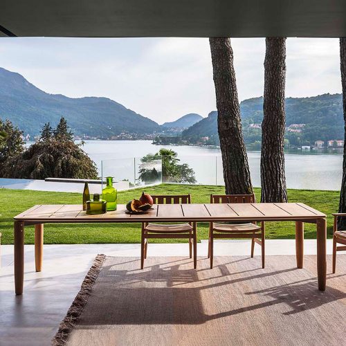 Levante Thirty Table outside with a large lake in the background, some trees, and the table is on a patio