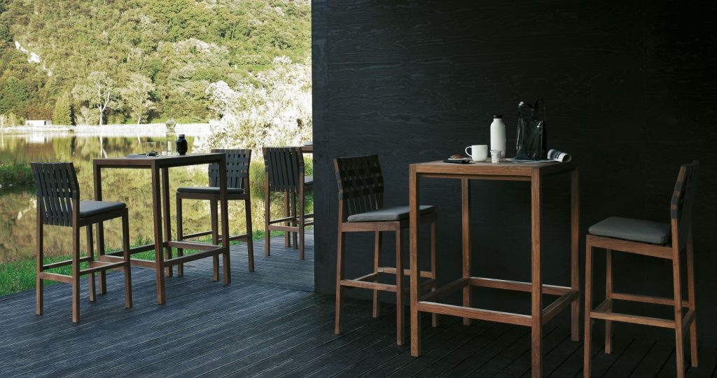 A few of Plaza Sixty Eight Counter Height Table with a stool at each table on a dark wood in front of a dark wall