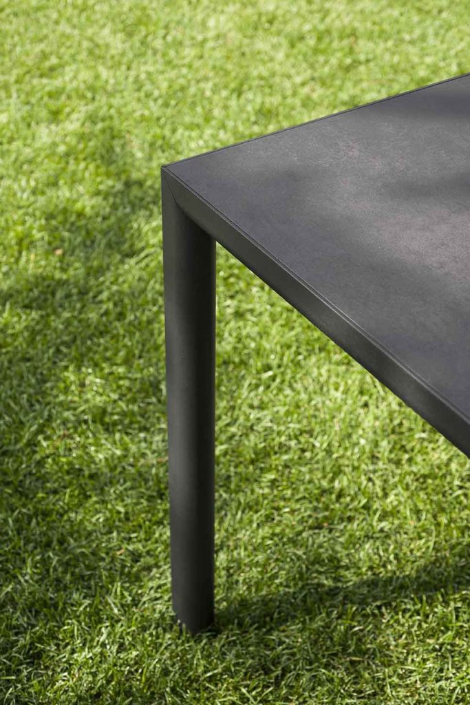 Close up of top of Plen Air Six Table on top of some grass