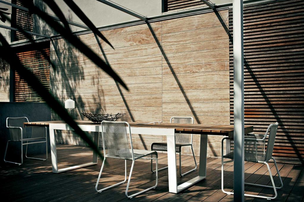 Spinnaker Thirty Four Extendable Table in front of a wooden wall with a chair on either side of the tablw