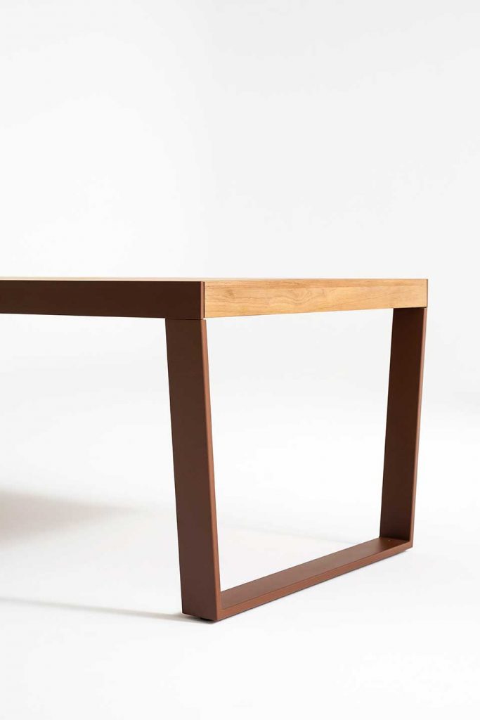 Close up of the edge of Spinnaker Thirty Four Extendable Table in a light wood finish in front of a white background