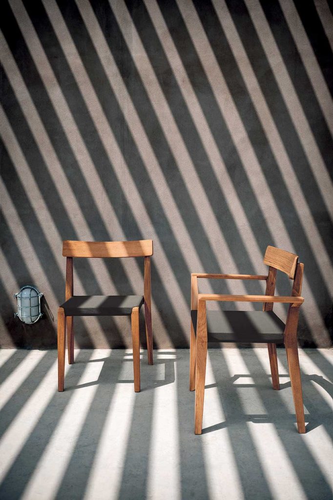 Pair of Teka Armchair om front of a grey wall with shadow stripes going over the chairs and wall