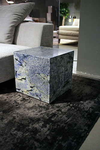 Qbic small cube shaped side table on a marble floor with a sofa to the left side