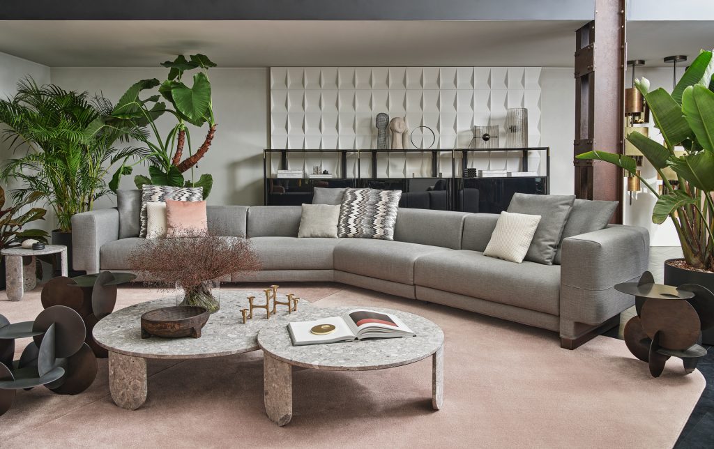 Grey colored Elissa Sectional on top of a pink rug with a Clemo round marble coffee table in front and a shelf behind the sofa