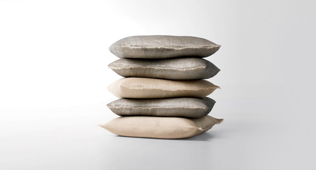 Cushions Abaca stacked on top of each other in front of a white background