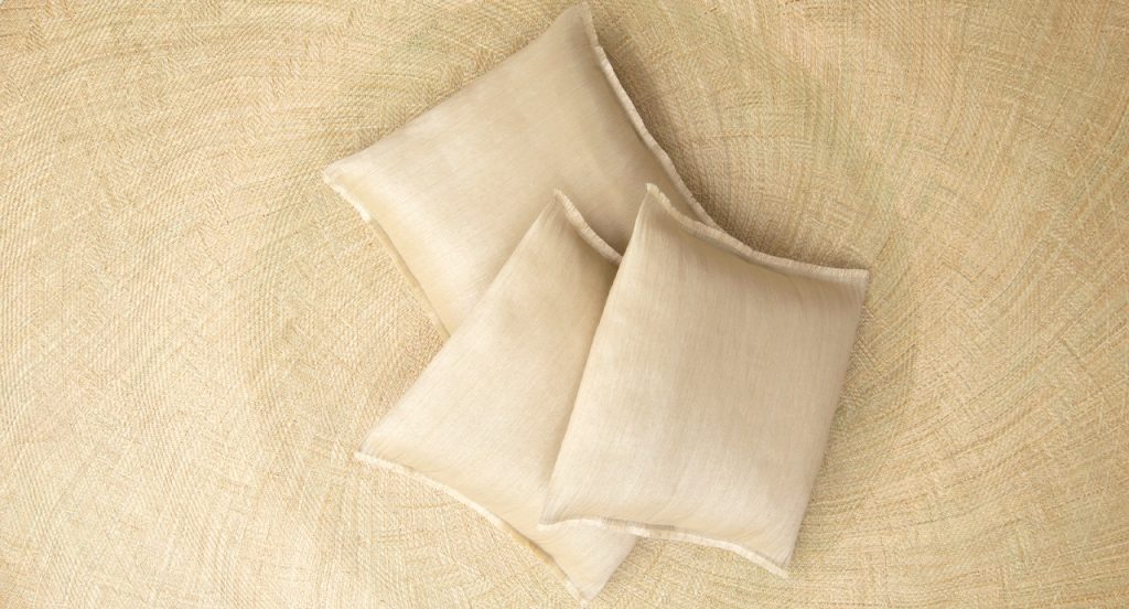 Cushions Abaca in a cream color on top of a light tan background