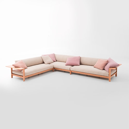 Frei Sofa in a cream color with pink pillows on top in front of a white background