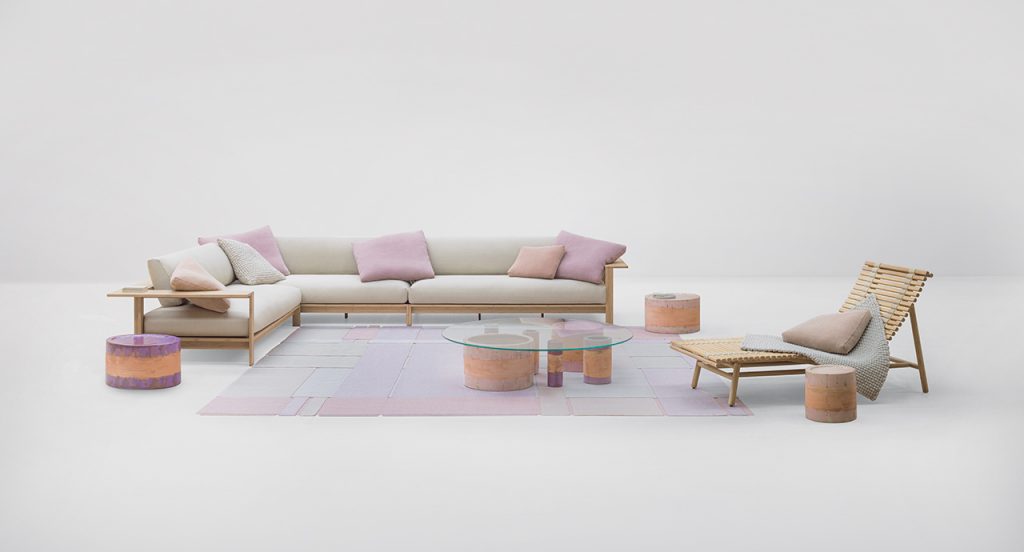 Cream colored Frei Sofa with a multicolored rug in front and a pair of small tables on top in front a of a white background