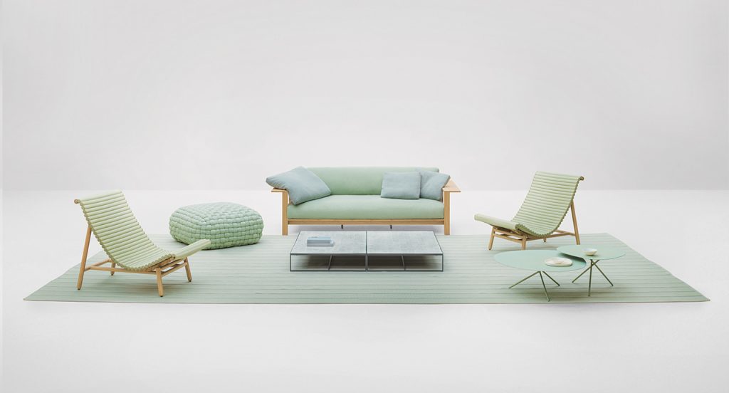Frei Sofa in a light green color with two light green arm chairs to the side with a light green colored rug in front