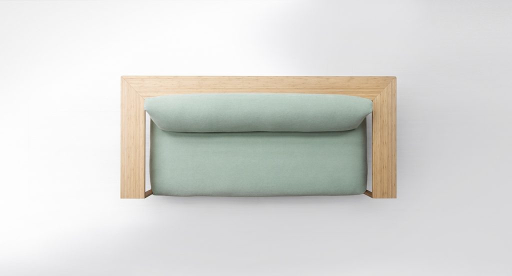 Close up side view of Frei Sofa in a light green color in front of a white background