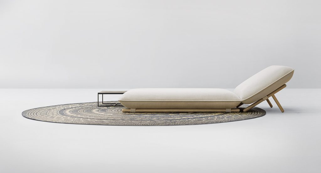 Side view of Hiro Chaise Longue on top of a grey rug in front of a white background
