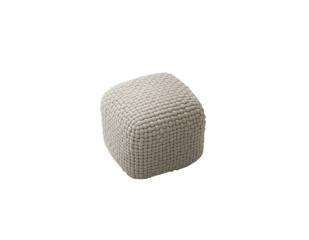Square ottoman with softly rounded edges, upholstered in a textured beige fabric with a grid-like woven pattern.
