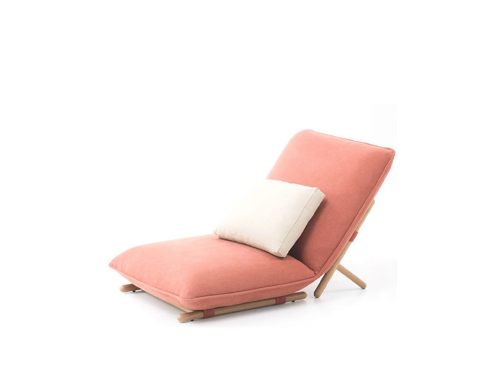 A modern outdoor lounge chair with soft coral fabric, reclined backrest, and light wooden legs, completed by a cream cushion for added comfort.