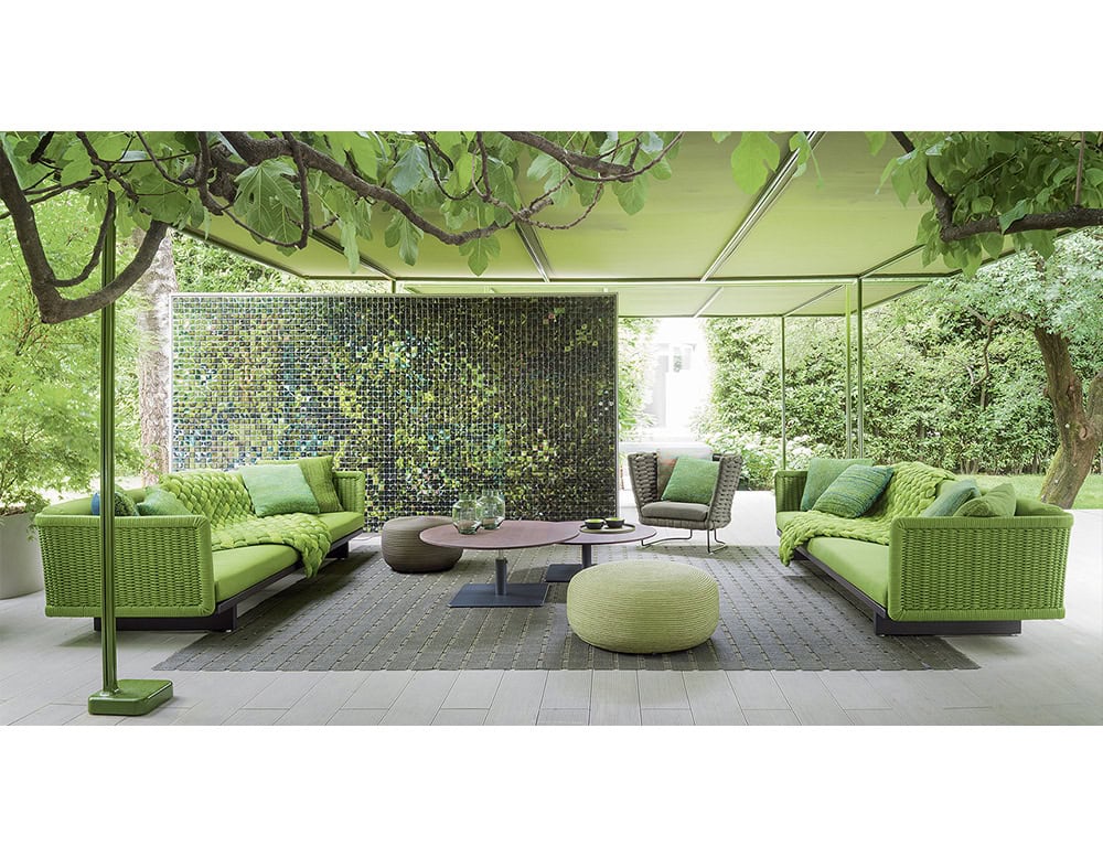 Comfort meets style in this garden lounge. The structured sofas and soft poufs anchor the space with bold color, while minimalist tables balance the look for a serene outdoor setting.