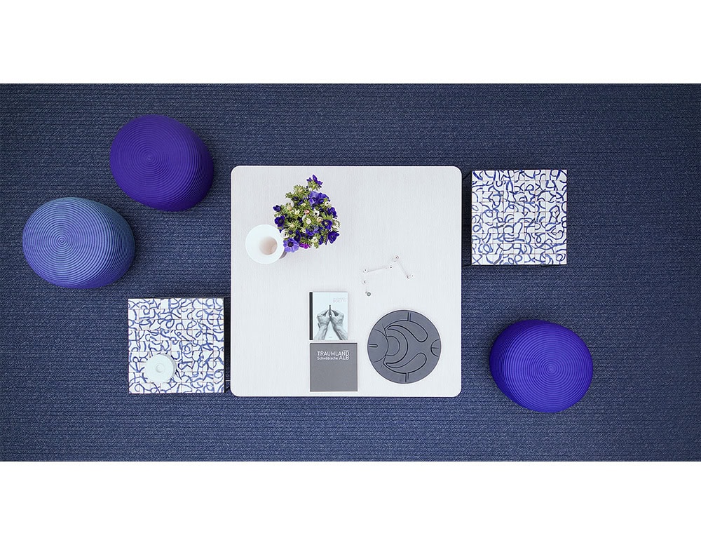 Vibrant poufs in rich purples circle a sleek white table, creating a bold yet inviting arrangement. Their textured design adds depth and comfort to this modern setup.