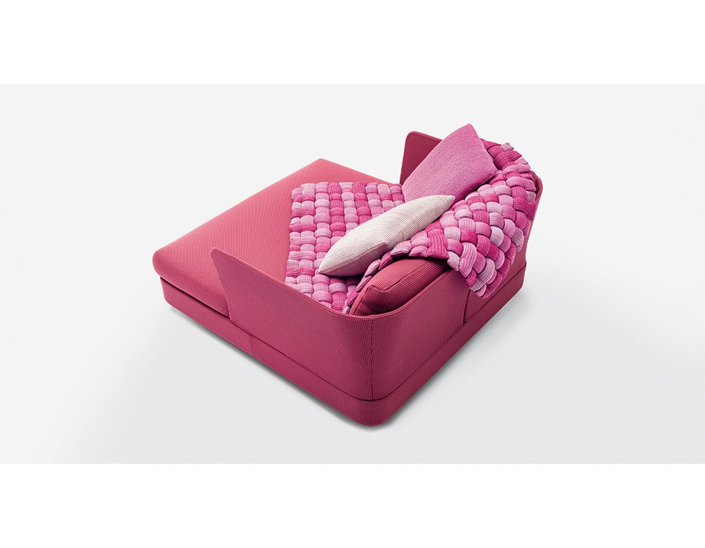 Bold pink lounge seat styled with a woven throw in vibrant pink and soft lavender, complemented by textured pillows for a playful yet cozy accent.