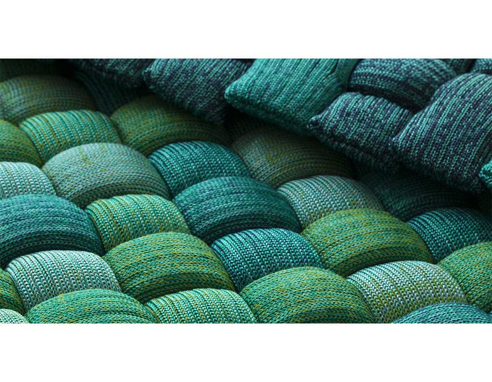 Detailed view of soft, interlaced fabric pads in layered shades of green and blue, highlighting tactile richness and artisanal quality.