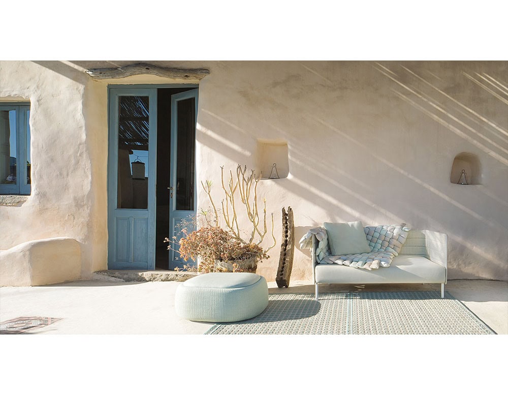 Cozy patio scene featuring neutral-toned furniture with woven details and pastel accents, creating a calm balance against warm stucco walls and natural light.