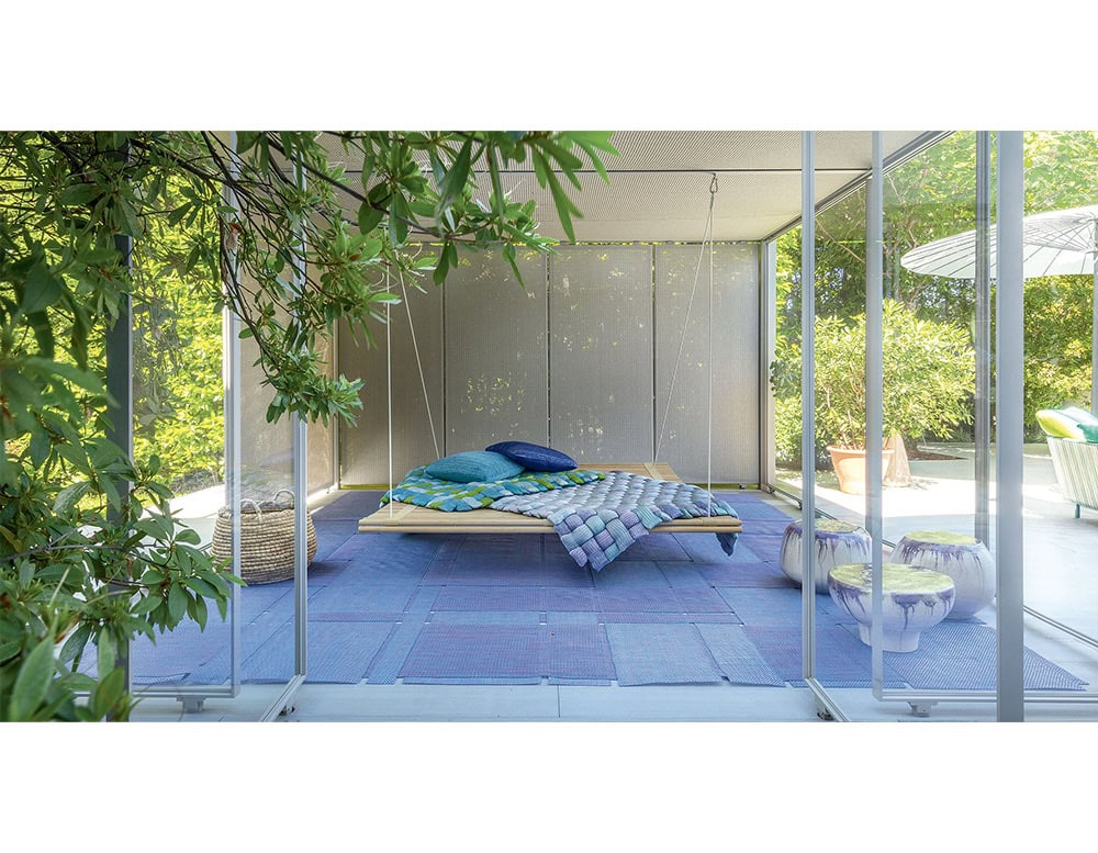 This hanging platform bed with vibrant quilted accents creates a cozy and stylish focal point. Its airy structure invites relaxation while enhancing contemporary outdoor living.
