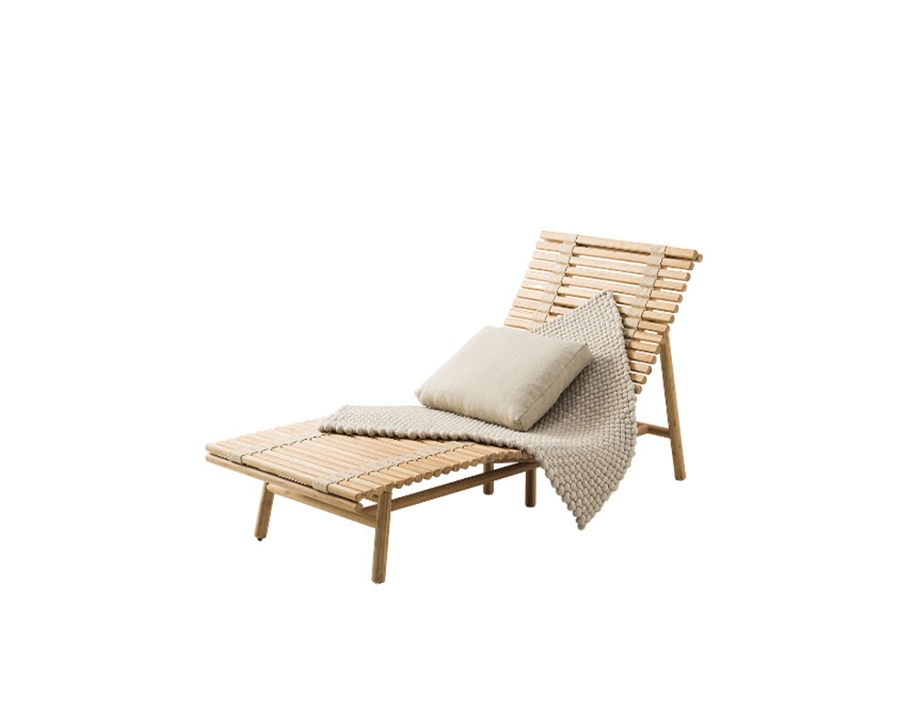 A wooden lounge chair with a slatted design complemented by a soft cushion and textured throw creating a relaxed and natural aesthetic.