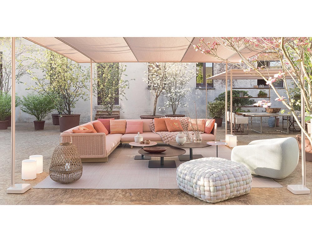 A serene outdoor setting with soft-toned seating and woven poufs creates a welcoming lounge atmosphere, blending textured craftsmanship with comfort for refined relaxation.