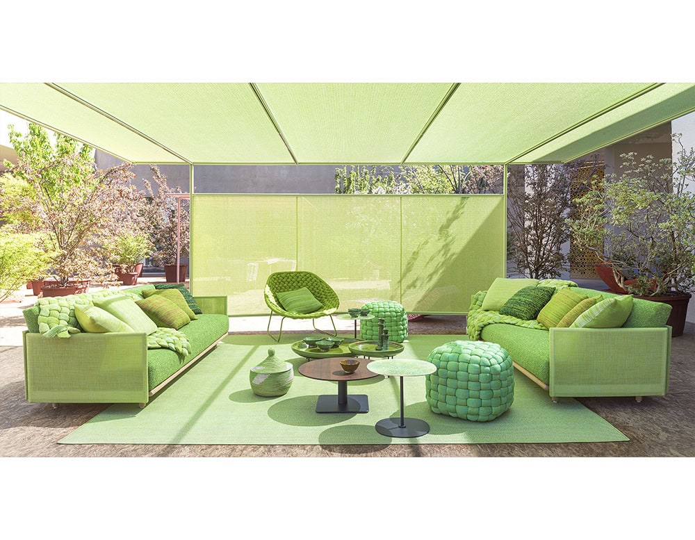 Bright green sofas, poufs, and chairs define this outdoor lounge with bold woven textures and layered cushions that create a fresh and vibrant atmosphere.
