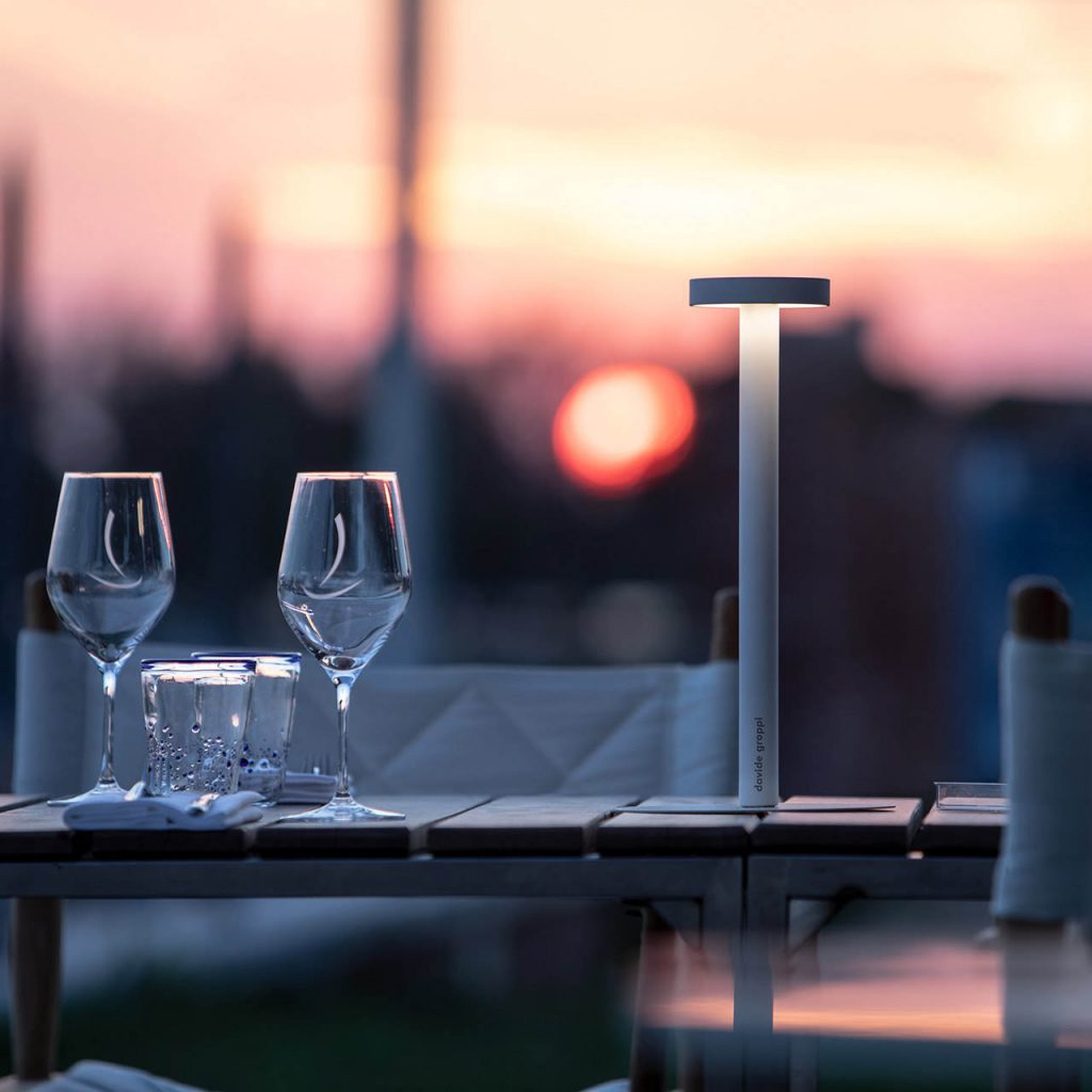 Tetatet table lamp next to two wine glasses with a sunset background