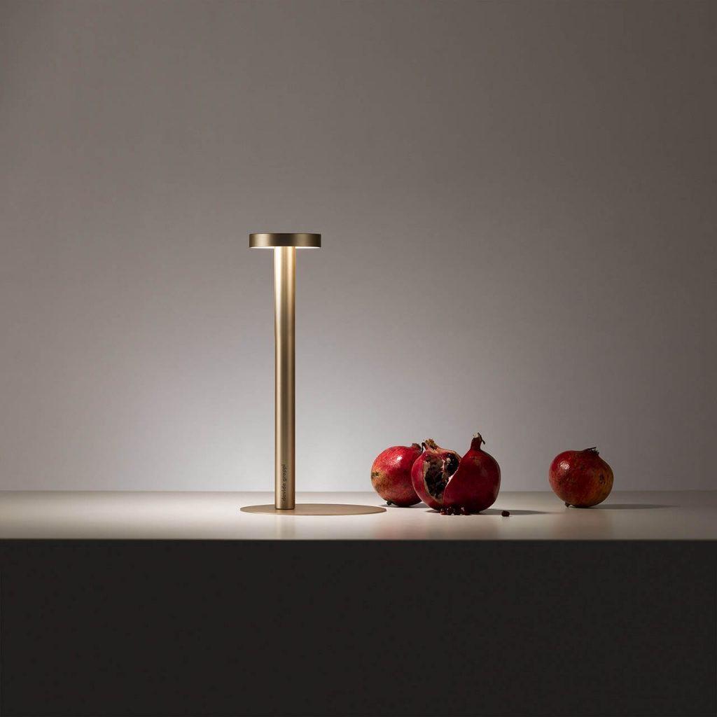 Tetatet table lamp next to some apples in front of a white wall