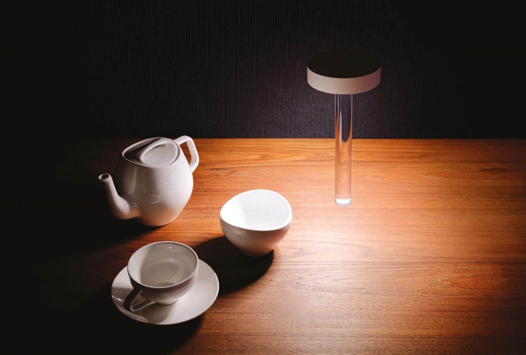 Tetatet flute light on a wood table with a tea set next to it