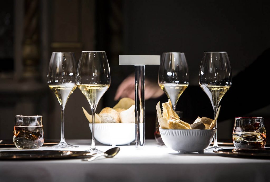 Tetatet flute light on a table with wine glasses surrounding it