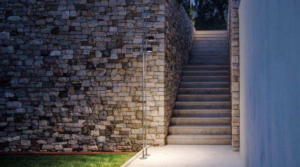 Bubka outdoor lamp shining on a stone walkway with a stone staircase in the background