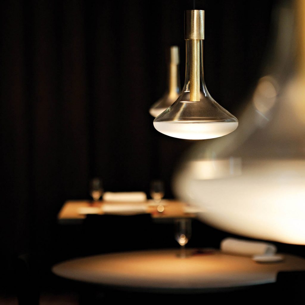 Three Cathode lights in a row illuminating three separate wooden tables