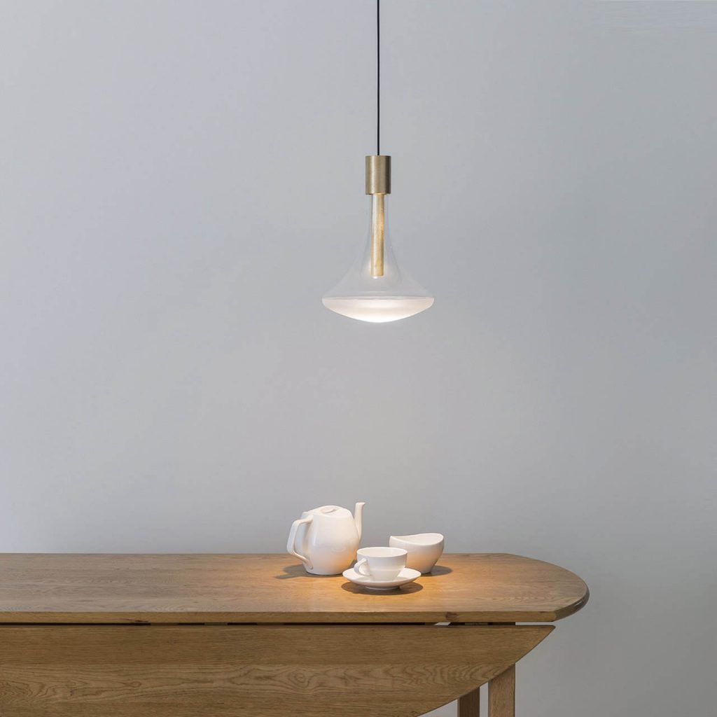 Cathode light illuminating a wooden table with some small objects on top in front of a white wall
