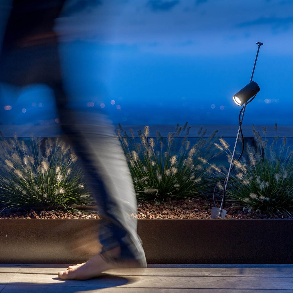 Grillo outdoor lamp pointed at a walkway with a person walking in front