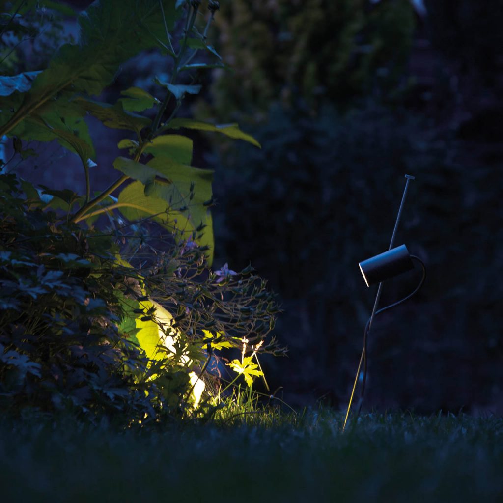Grillo outdoor lamp shining at a tree with grass underneath