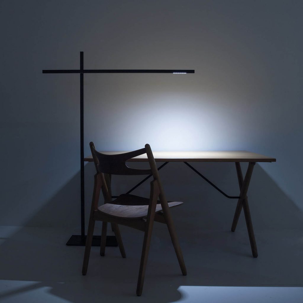 Hashi floor lamp illuminating a wooden desk with a wooden chair in the foreground