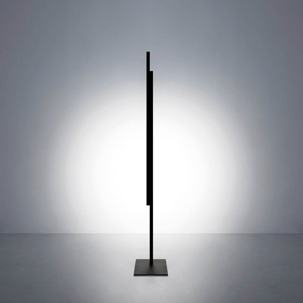 Hashi floor lamp in a vertical position shining at a white wall