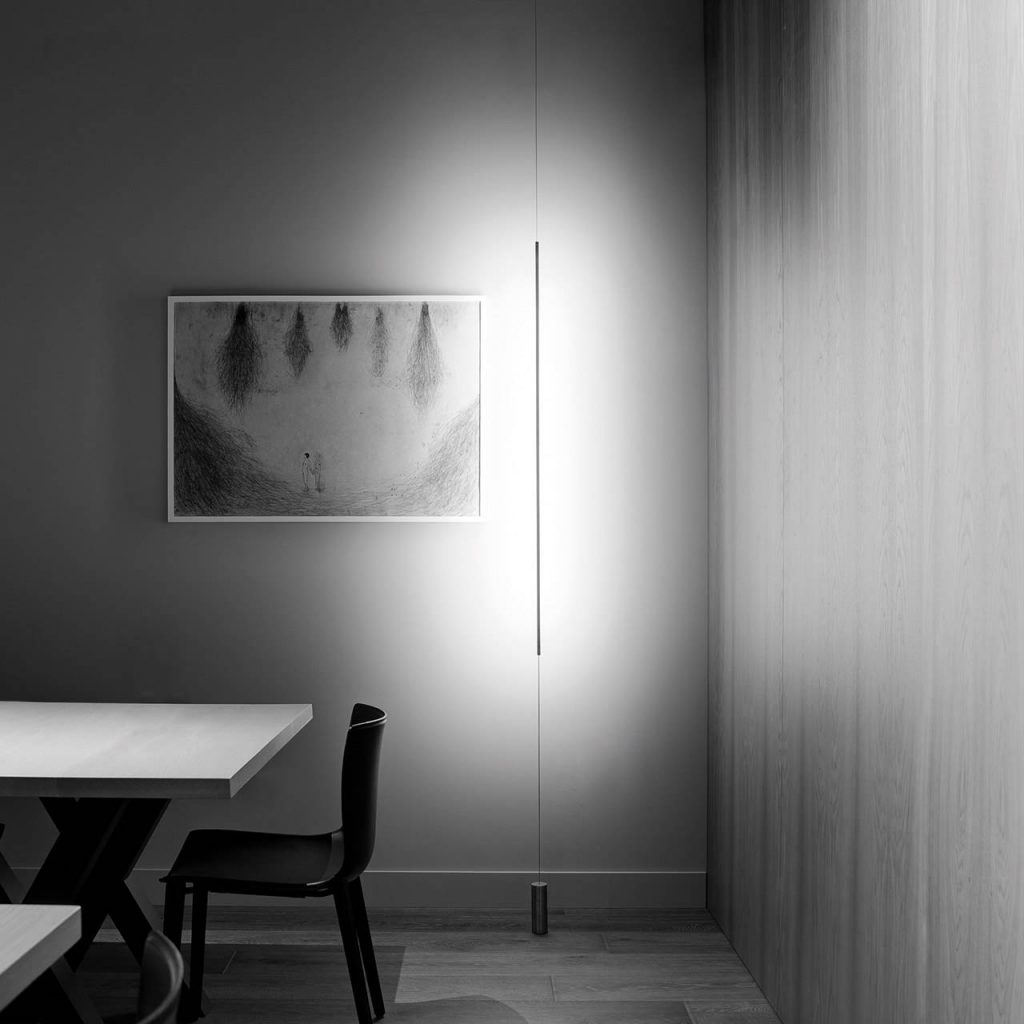 Masai light shining against a grey wall with a white table to the left side of the room