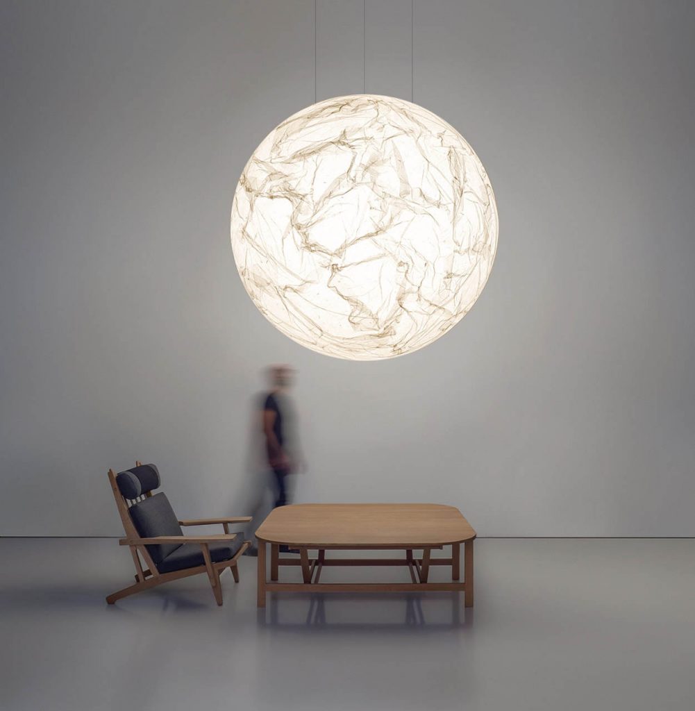 Medium sized Moon light illuminating over a wooden table in a grey walled room