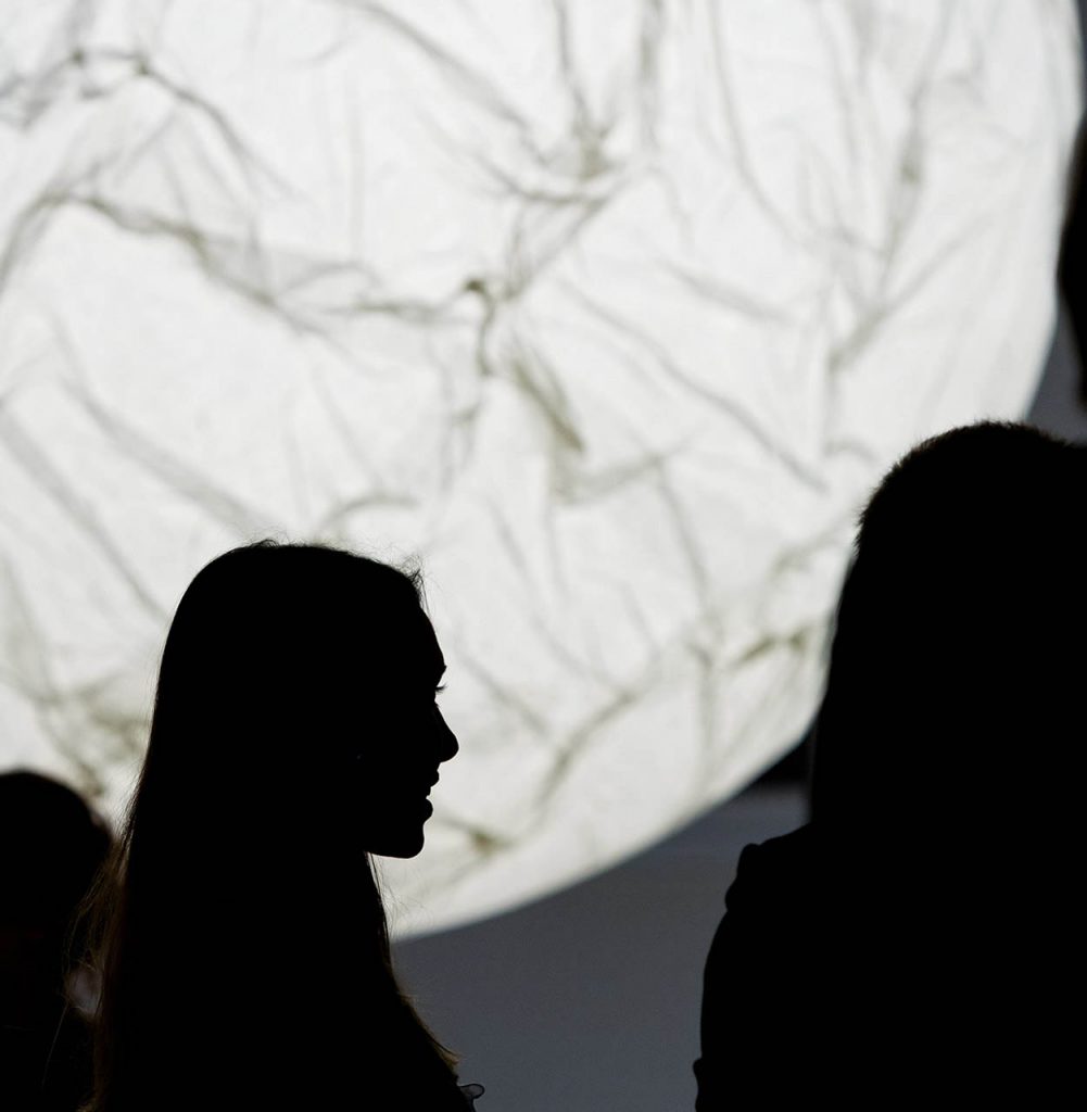 Moon light illuminating behind three individuals in a dark room