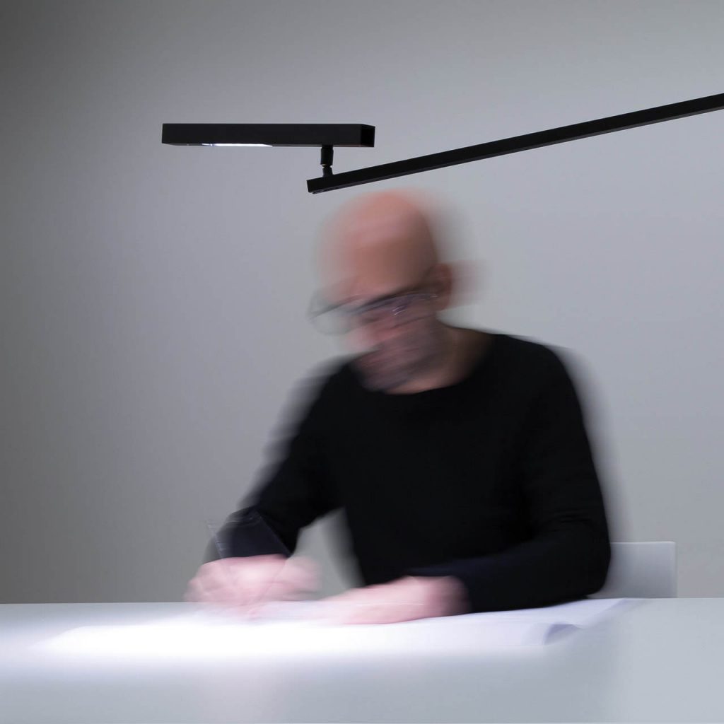 Morsetto desk lamp in illuminating a white desk with a person sitting in front of the lamp