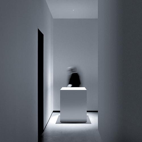 Nulla light shining over an art piece on a a white pedestal in a white room
