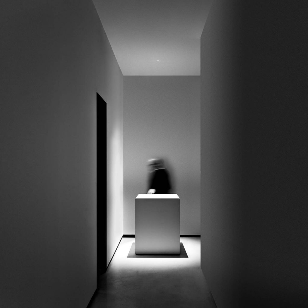 Nulla light shining over an art piece on a a white pedestal in a white room