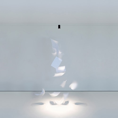 Ohm light shining over a white art piece in a white room