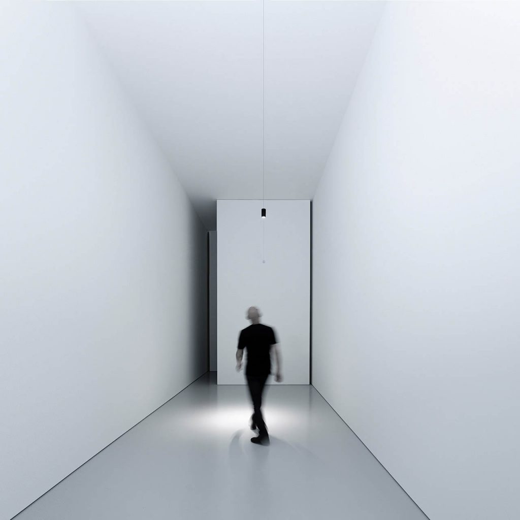 Ohm light shining over a person in a white walled hallway