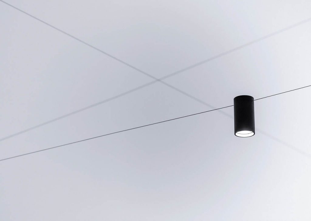 Close up of Ohm light on a wire underneath a white ceiling