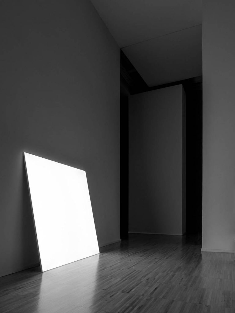 Pablo shining in white in a dark lite room