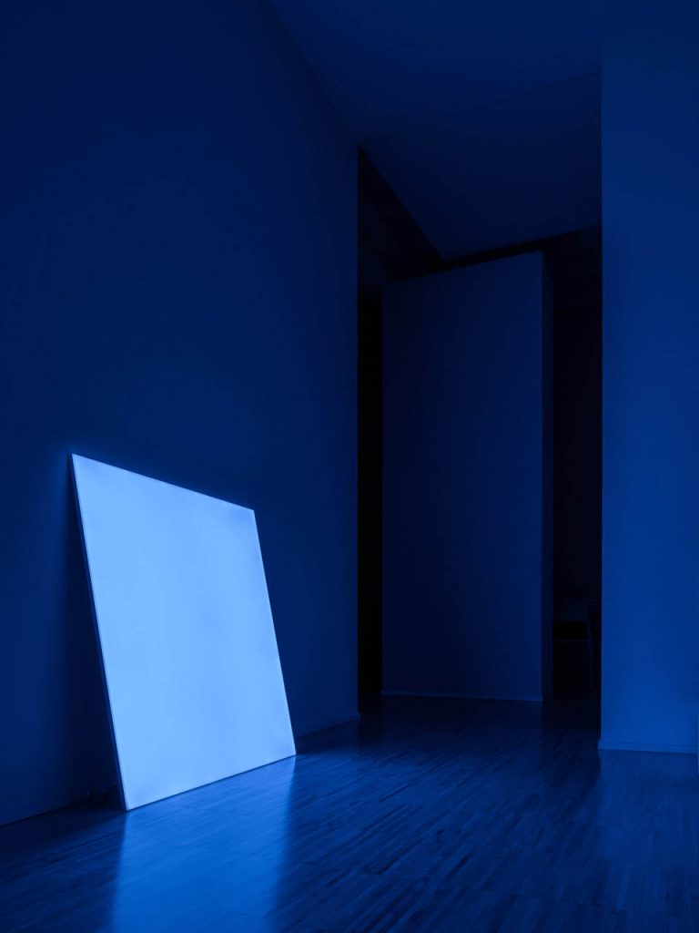 Pablo shining in blue in a dark lite room