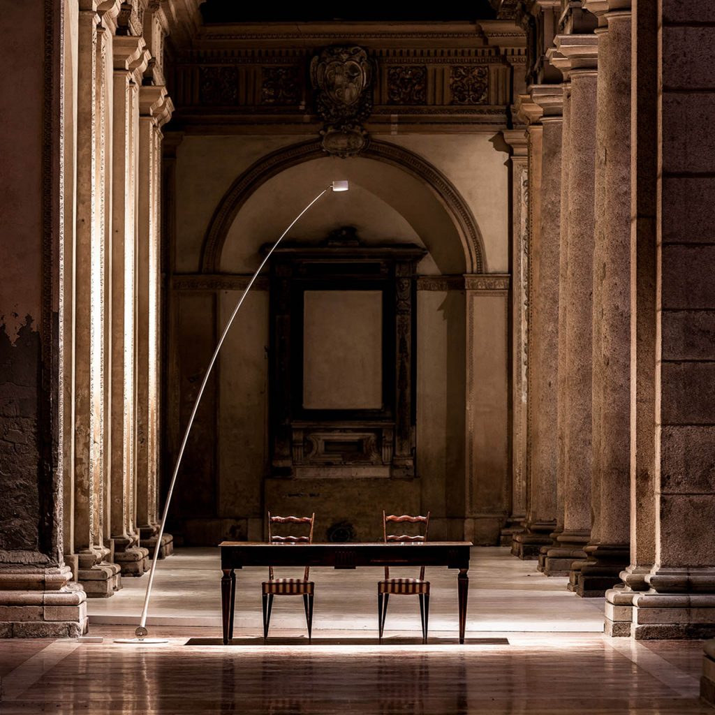 Sampei light illuminating a table in the middle of a hallway with pillars surrounding the light and table